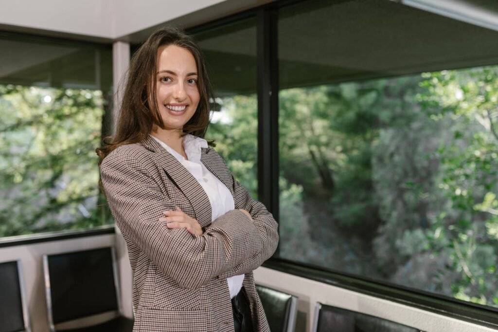 pexels photo 7648307 Portrait of a smiling businesswoman in an office with large windows.