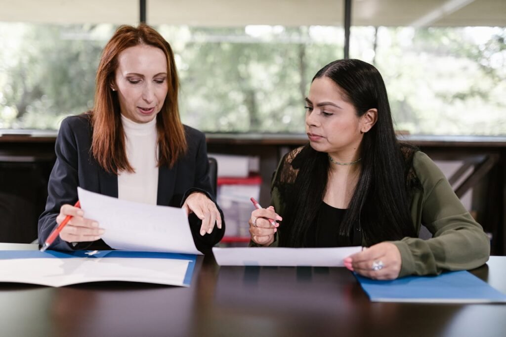 pexels photo 7648470 Two professional women reviewing documents in a well-lit office setting.